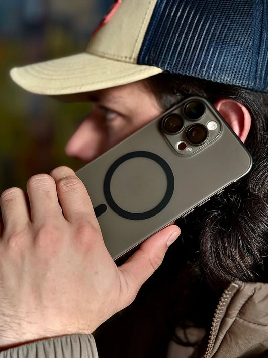 Hombre simulando llamada con iPhone protegido por carcasa Space Clear Súper Slim negra, vista lateral del MagSafe y protector de cámara