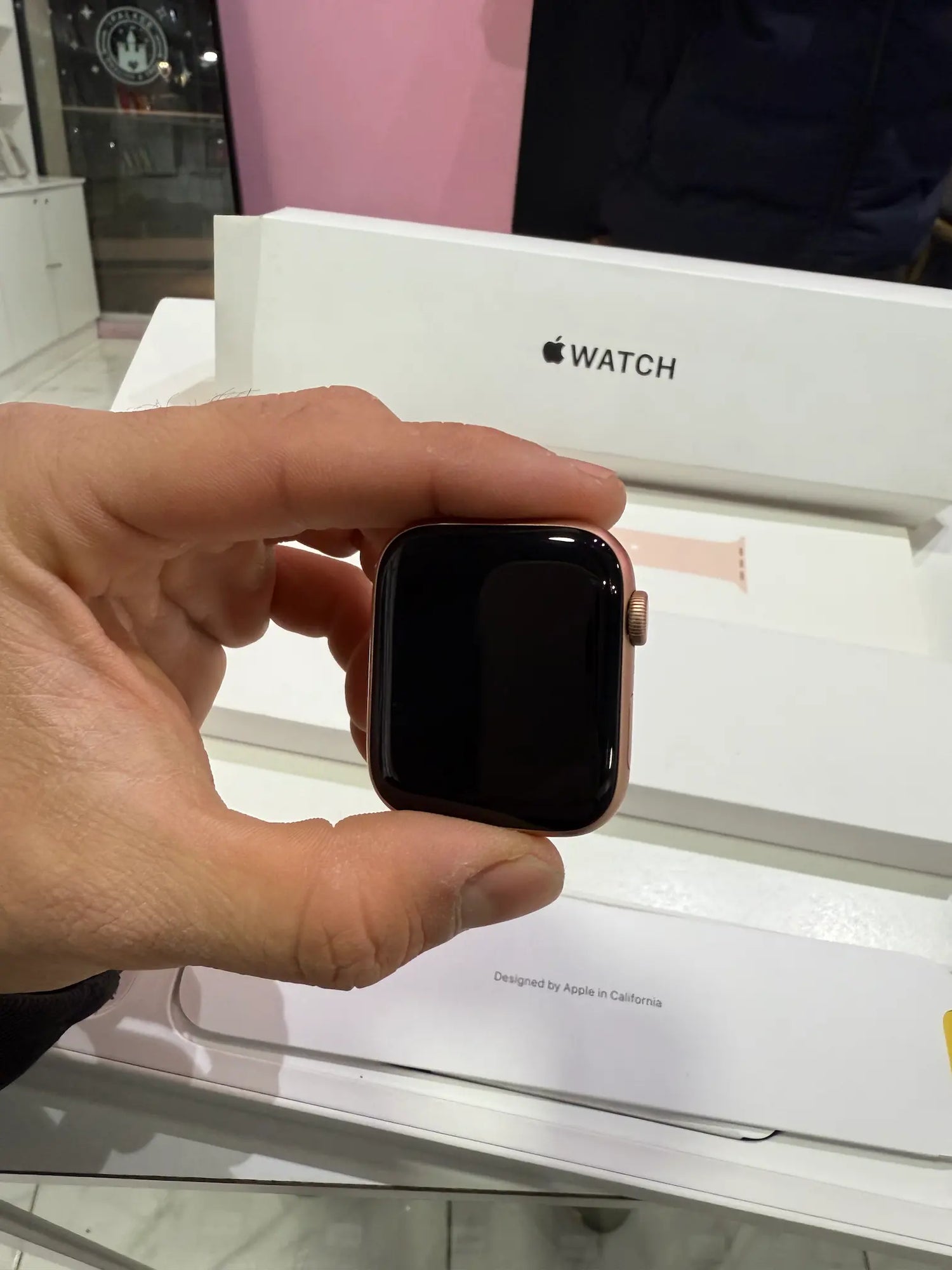  Apple Watch SE de 44mm tomado por manos masculinas y mostrando la caja del reloj